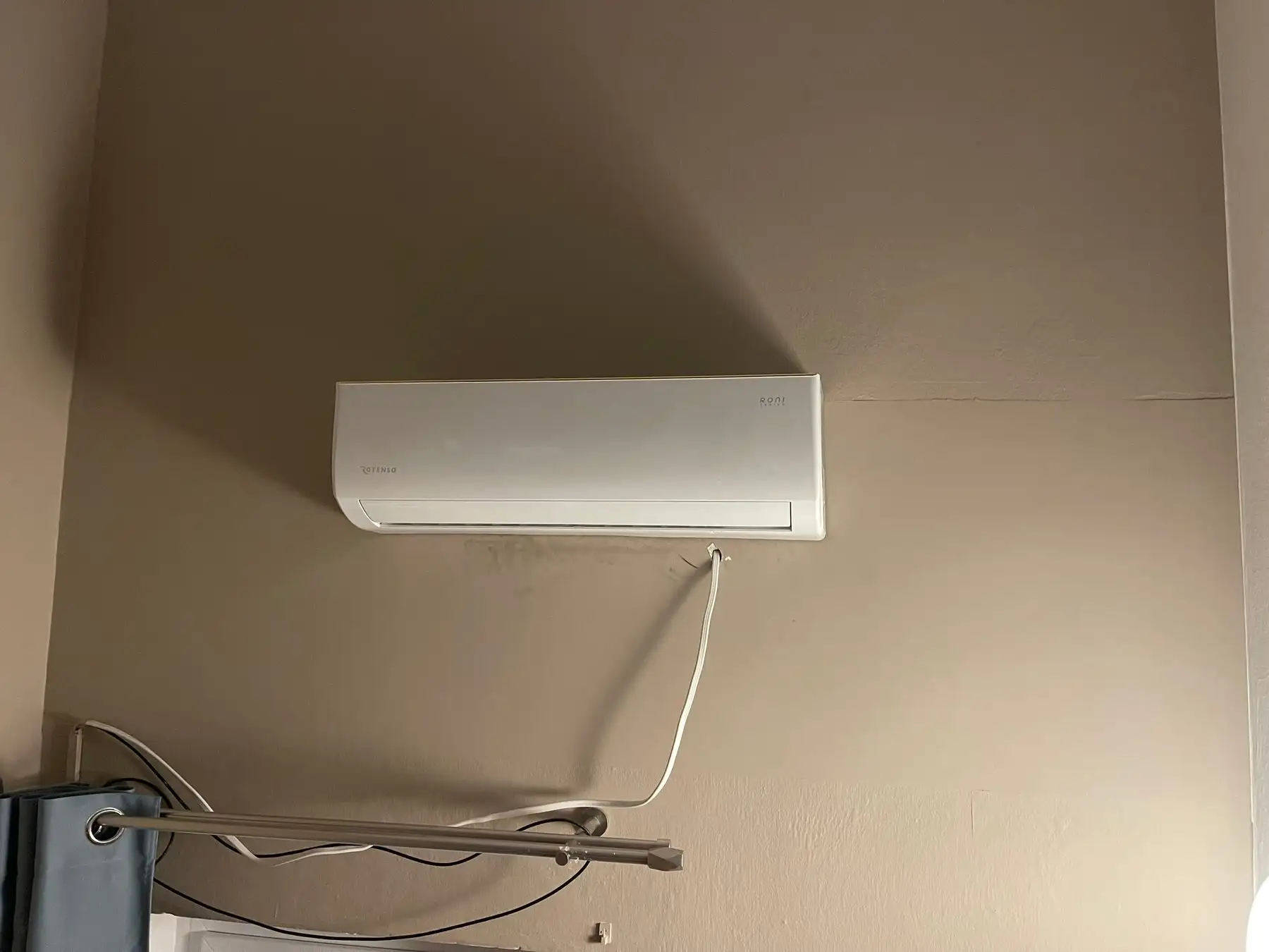 Klimatyzator ścienny zamontowany nad oknem w salonie